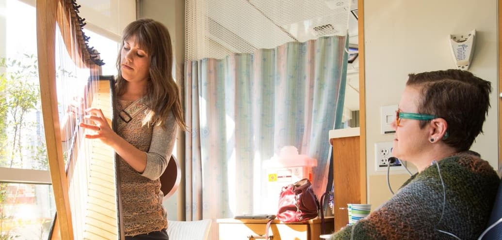 A graduate of SPU's music therapy program plays the harp as she works with a patient.