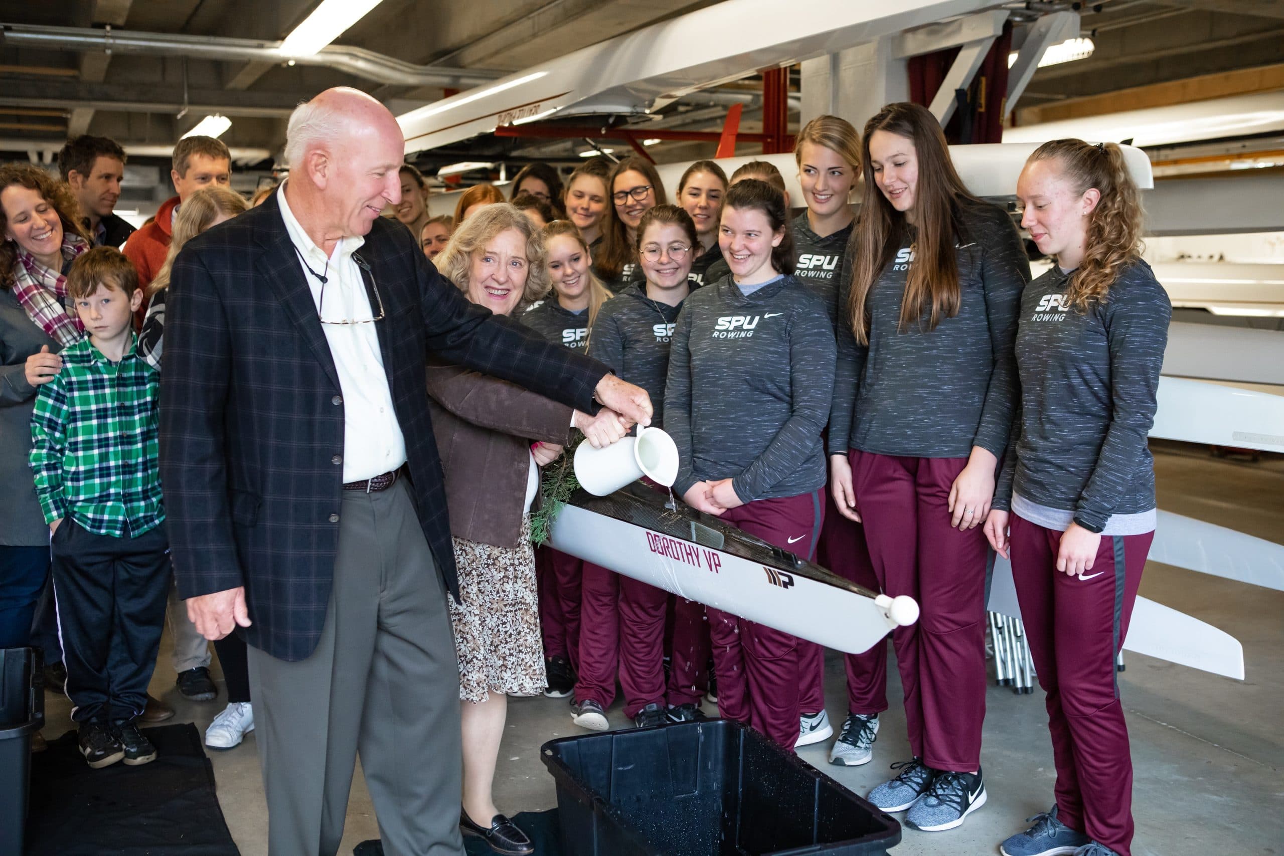 Daryl and Claudia Vander Pol and the women's crew team at the launching of a new Falcon racing shell.