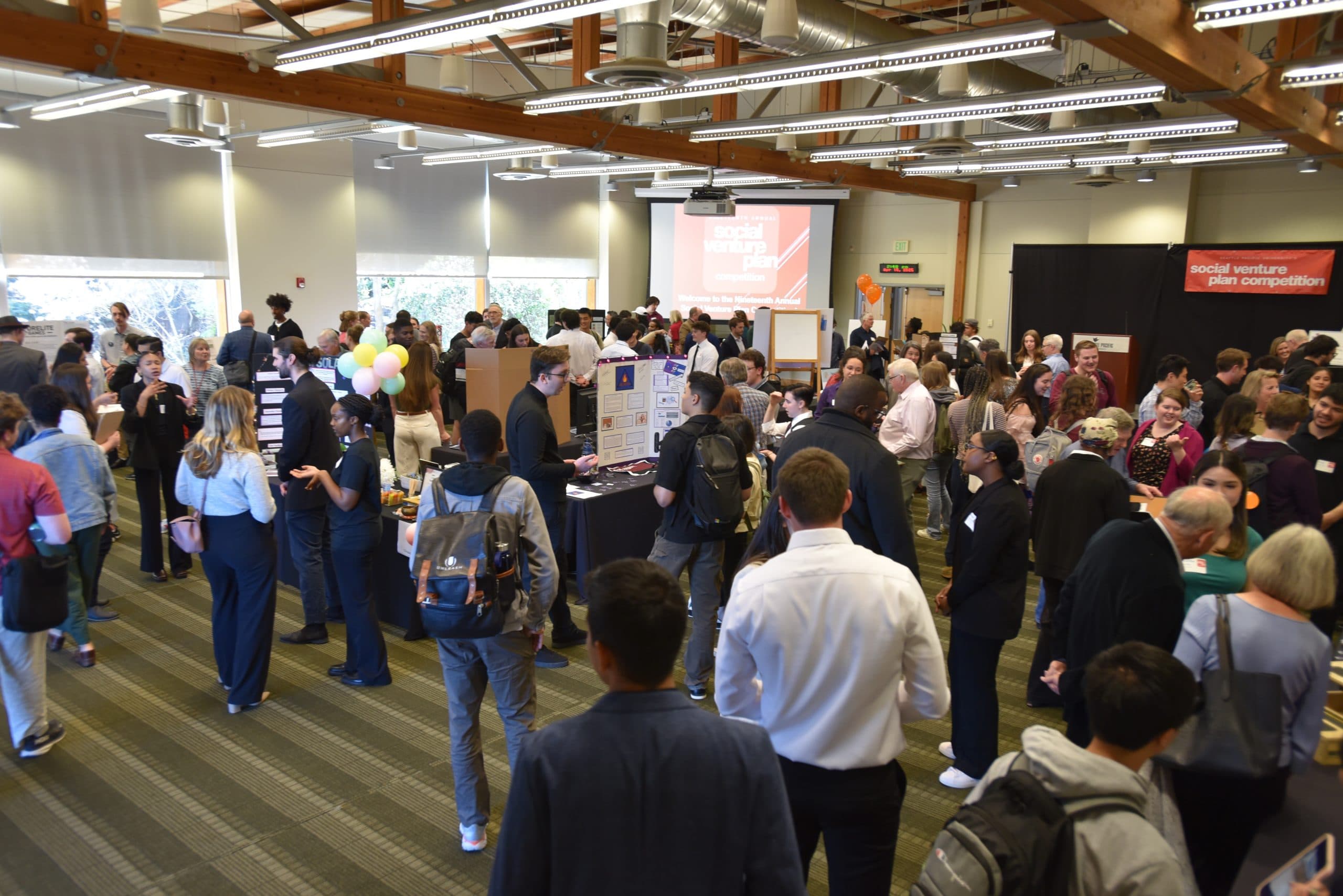 wide shot of Social Venture Plan Competition in April 2025. Crowds of people talking in small groups.