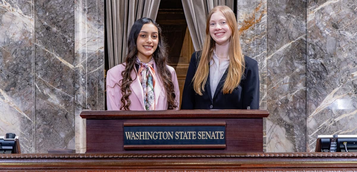 Karla and Sadie at a podium with Washington State Senate underneath. Courtesy of Washington state Legislature.