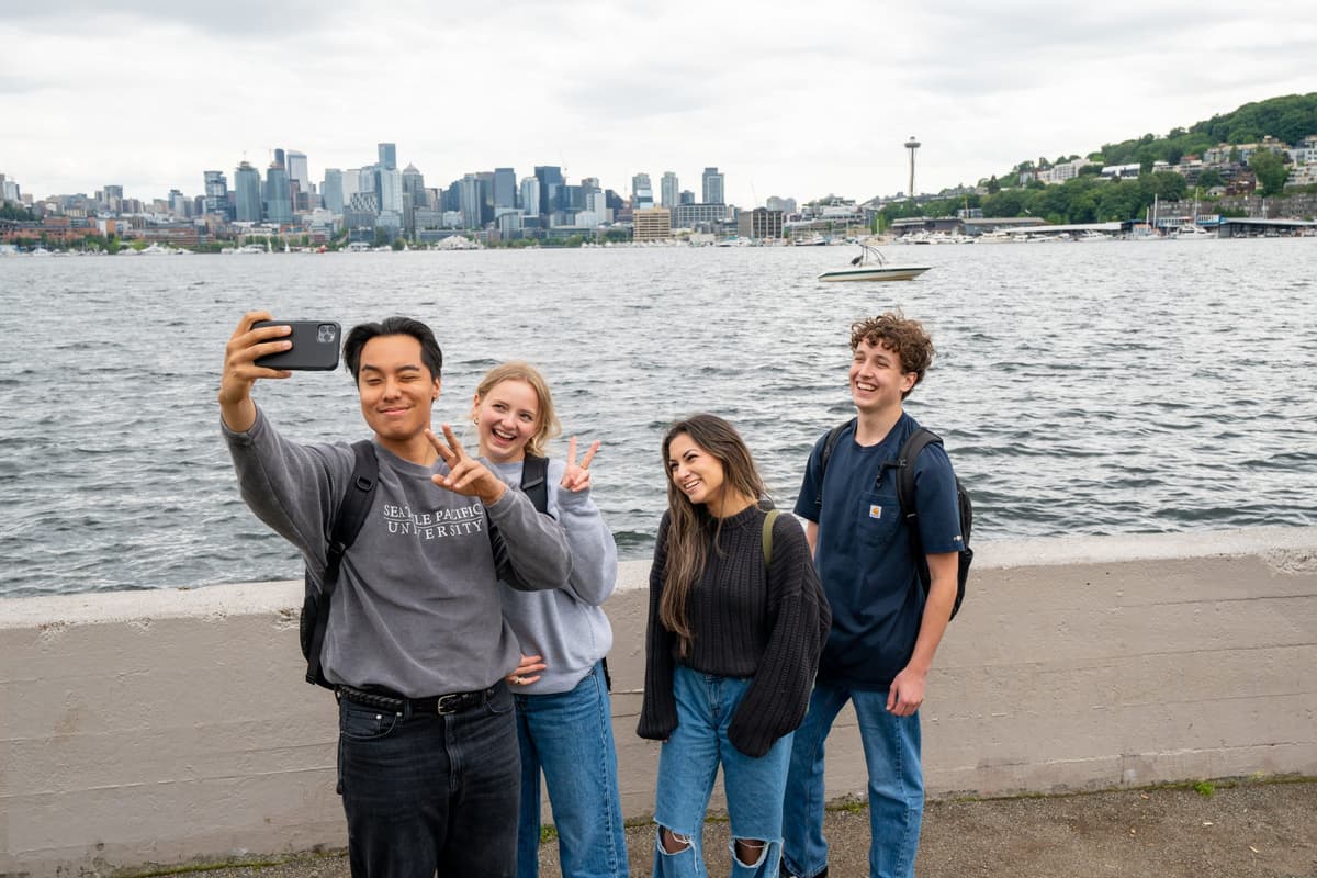 Students posing for a funny selfie with Lake Union and Seattle skyline in the background