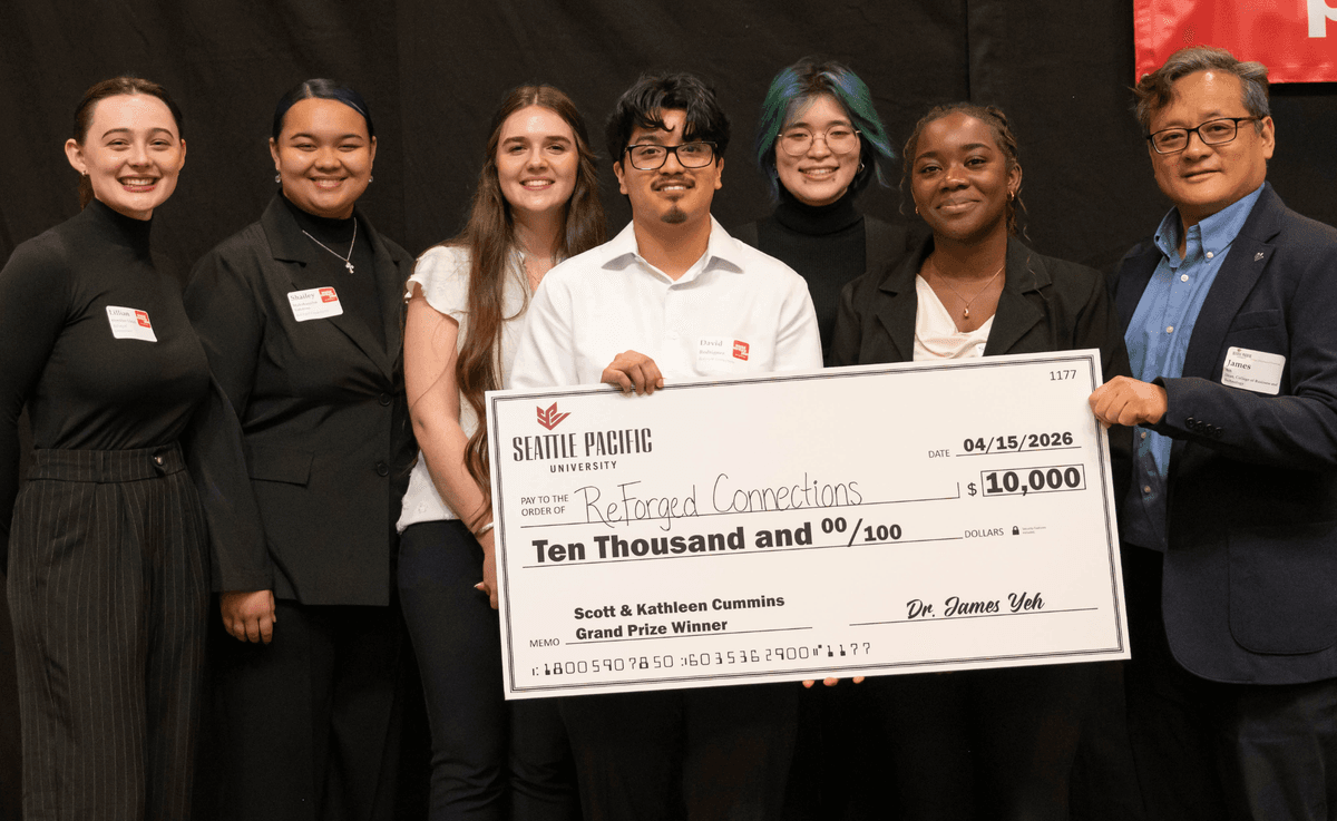 Six students and CBT Dean James Yeh hold a oversized check ten thousand dollars for ReForged Connections