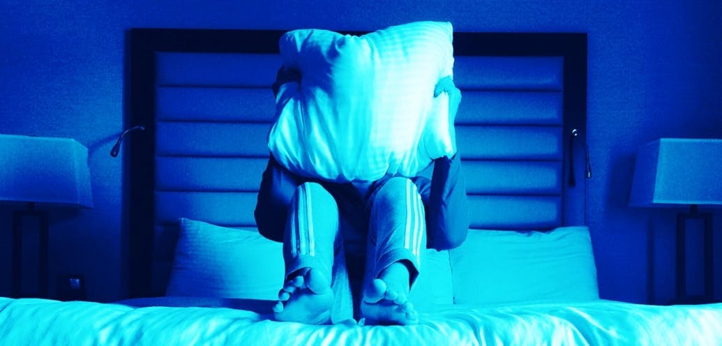 A person holds up a pillow in front of his or her face.