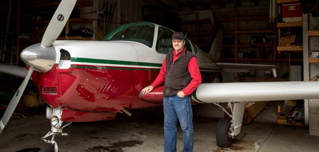 LeRoy Hubbert stands in front of his single-engine airplane.