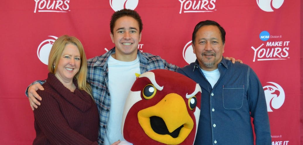 family poses with Falcon at homecoming family brunch