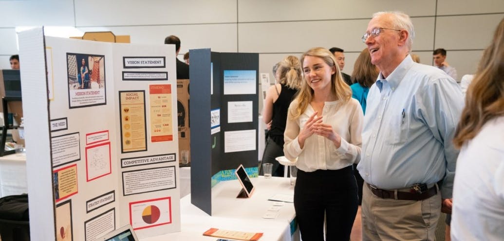 In this photo, a woman and a man look at a project poster.