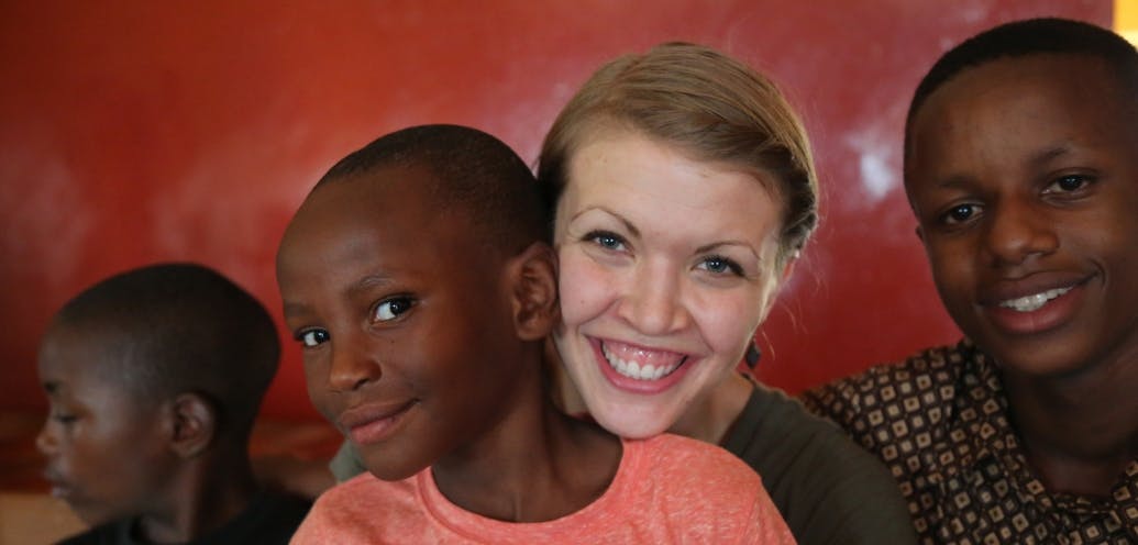 A smiling Megan Swanson Chao hugs Rwandan children.