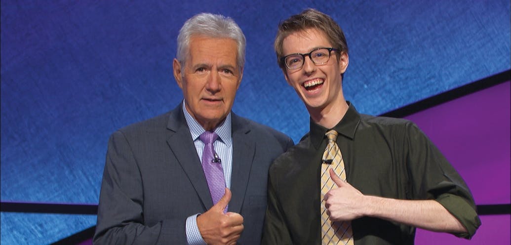 In this photo, Ryan Fenster gives a thumbs up while standing next to Alex Trebek.