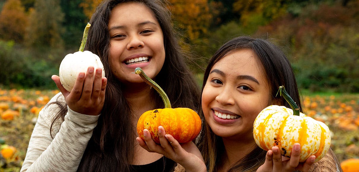 Two SPU students hold up pumpkins at Bob's Corn and Pumpkin Patch