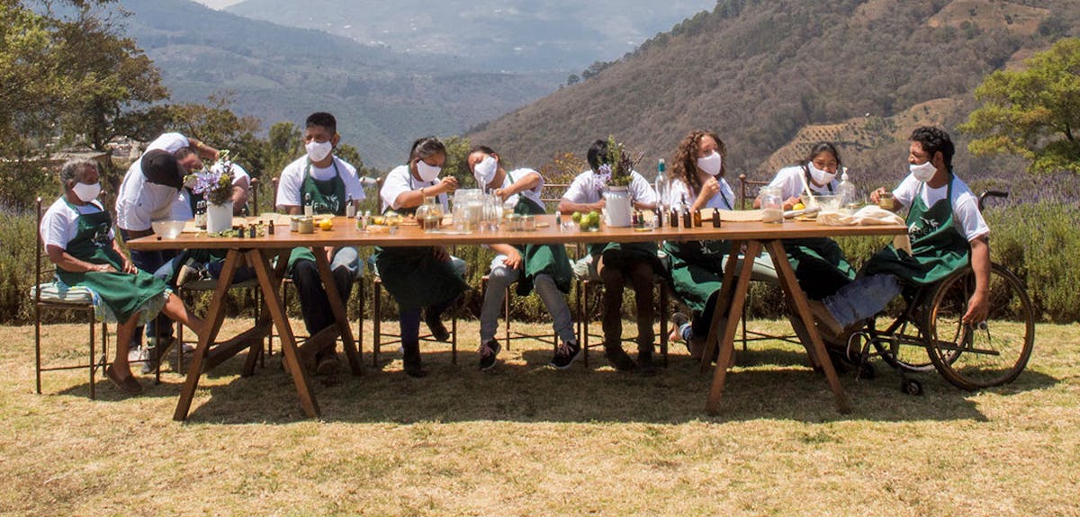 Eden Por Salud enjoy the weather as they prepare products around a long table