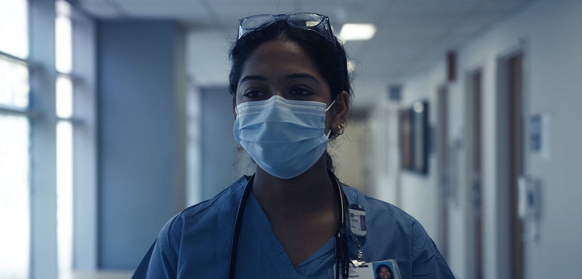 A screenshot from The Time to Heal portraying a nurse walking down the hall at Harborview Medical Center