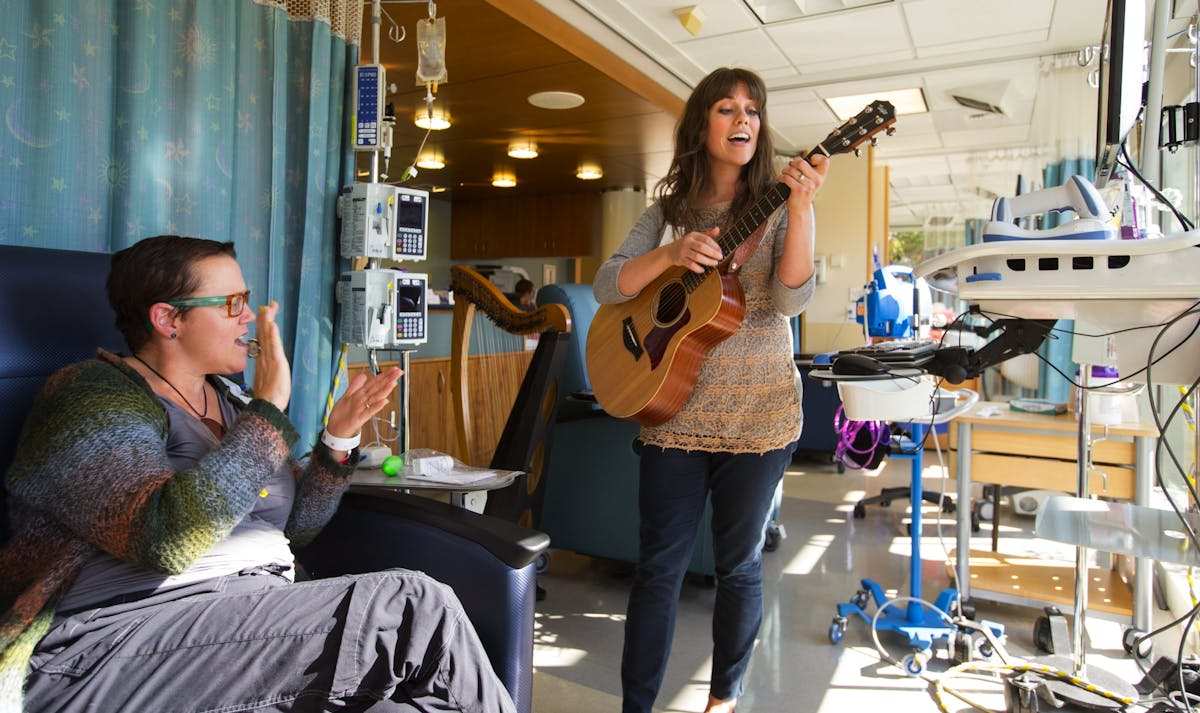 woman playing guitar to patient in hospital
