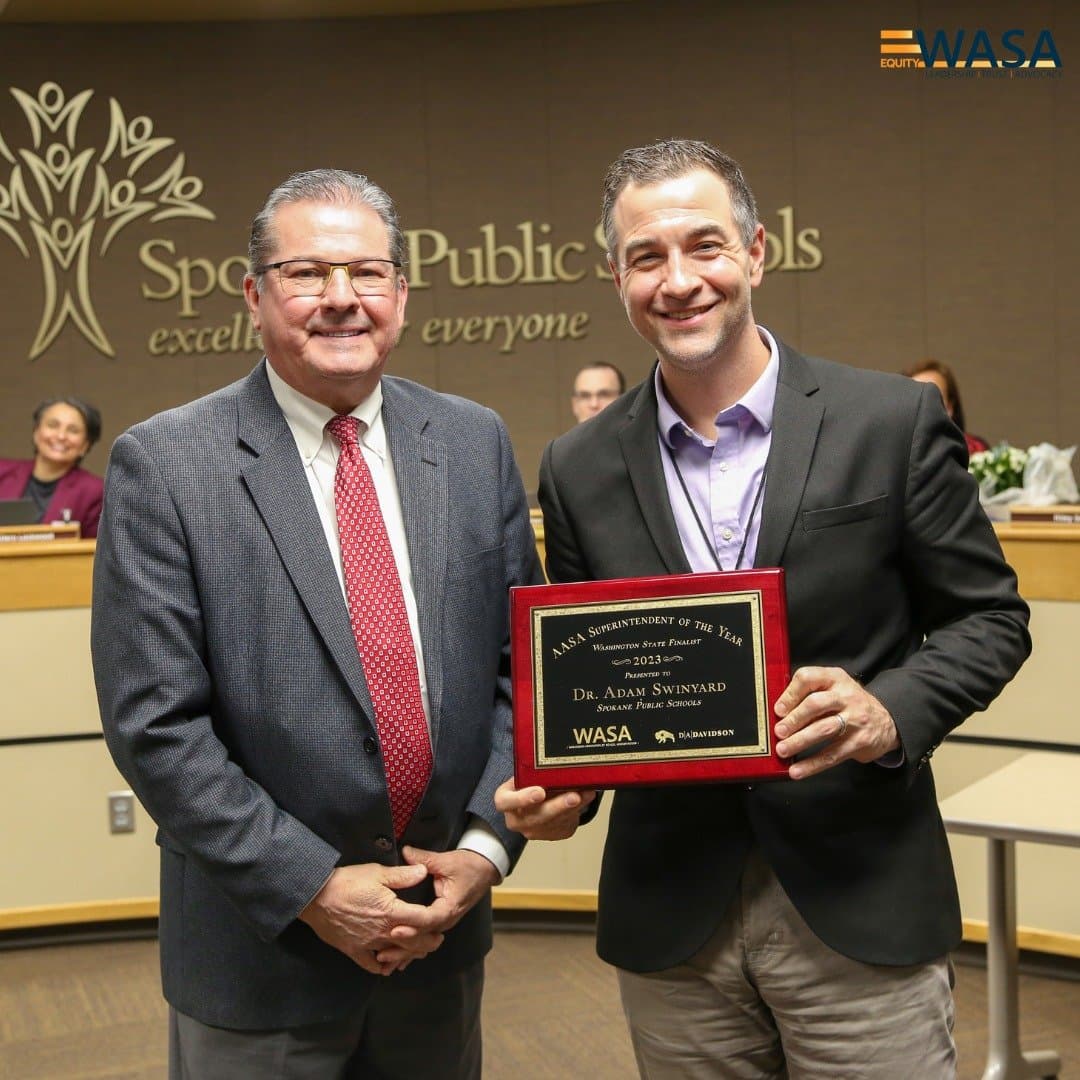 Two men standing holding an award plaque